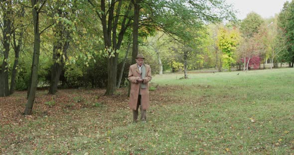 Senior Man on a Walk in Green Park Talking and Noting Something