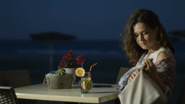 Smiling Young Lady Drinking Cocktail at Seaside Restaurant, Writing in Notebook