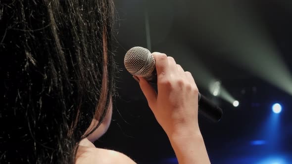 Closeup of a Beautiful Singer with Long Hair on a Dark Stage in the Spotlight