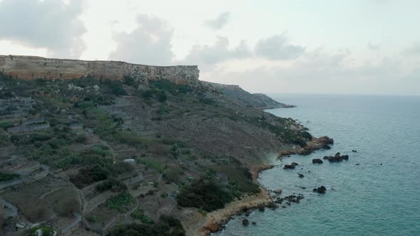 Coastline of Malta Island at Sunset with Cliff and Ocean Waves, Aerial Drone Perspective Forward