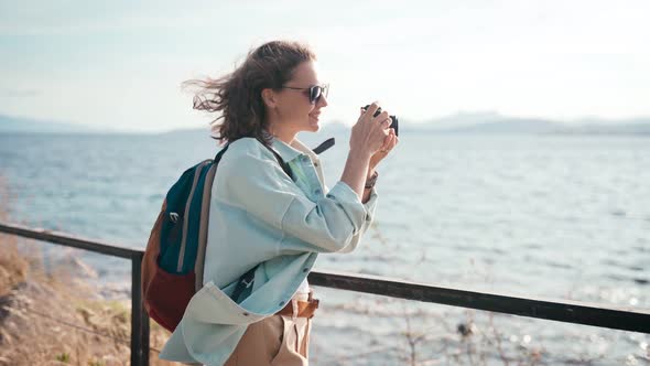 Happy Young Woman Takes a Picture on a Photo Camera Walking Sea, Summer Travel