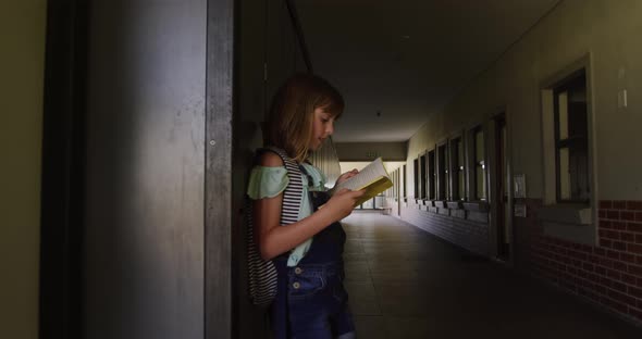 Girl reading books in the school corridor