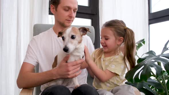 Little Girl and Father Cuddle Jack Russel Terrier at Home