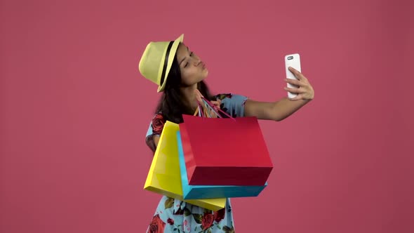 Teen Make Selfies with Colorful Packages. Pink Background. Slow Motion
