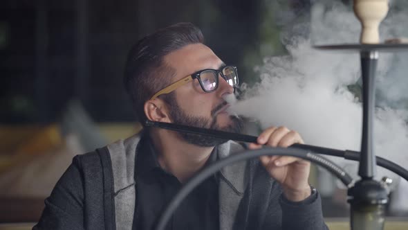 Close Up Shot of a Stylish Adult Guy Smoking Hookah Indoor of a Cafe Alone