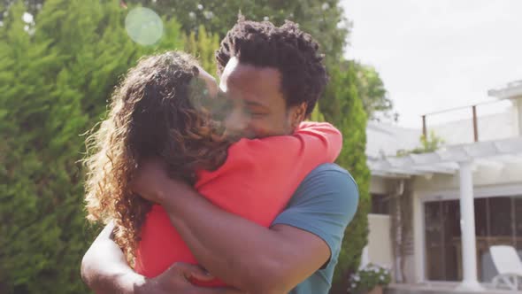 Happy biracial couple hugging each other after proposal in garden