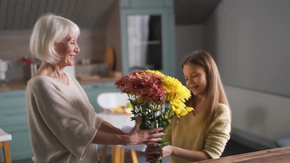 Positive girl with her grandmother holding a bouquet of flowers