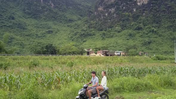 People Travel on Scooter at Rural Site Near Mountain Aerial
