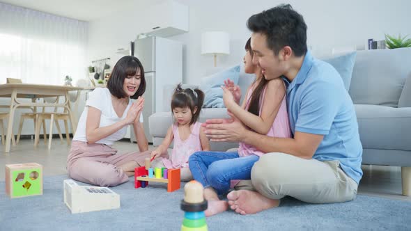 Asian young kid daughter coloring and painting on paper with parents at home