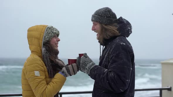 Portrait of Young People Man and Woman Hugging in Love While Drinking Tea or Coffee From Paper Cups