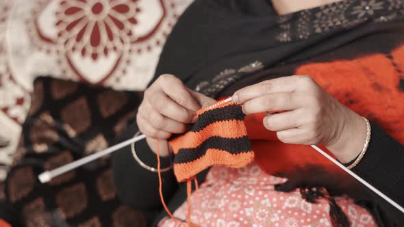 Traditional Indian woman knits with craft needles and black and red wool. 4k Close up footage of kni