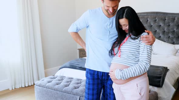 Pregnant couple interacting with each other in bedroom 