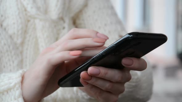 Business Woman's Hands Are Holding a Black Smartphone and Writing a Message