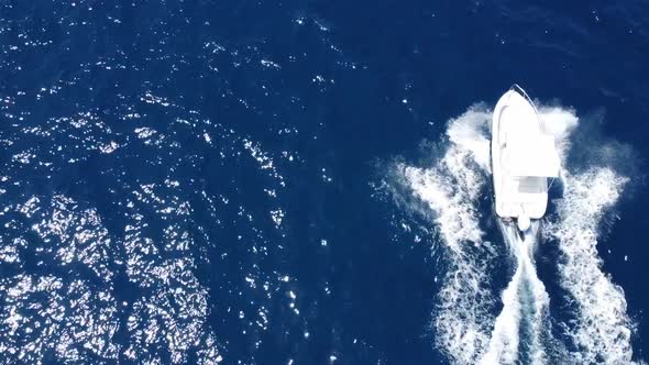 Aerial top down view of luxury speed boat moving on blue ocean making waves.Slow motion shot