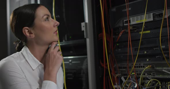 Caucasian female it technician pointing and checking computer server