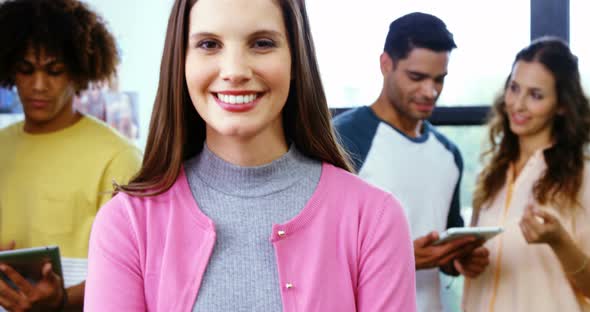 Smiling graphic designer standing with arms crossed while colleague discussing 