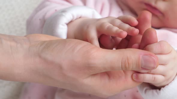 Baby Holding Mother Hands. Closeup.