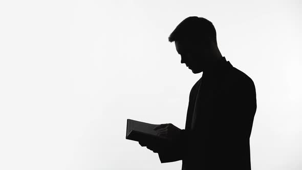 Silhouette of Businessman Looking Through Meeting Planner, Checking Appointment