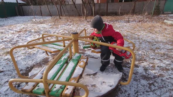 Boy Spinning On A Carousel In Winter Slow Motion