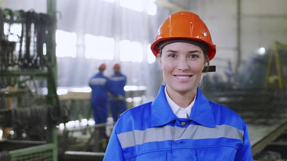 Smiling Caucasian woman staying in uniform at factory