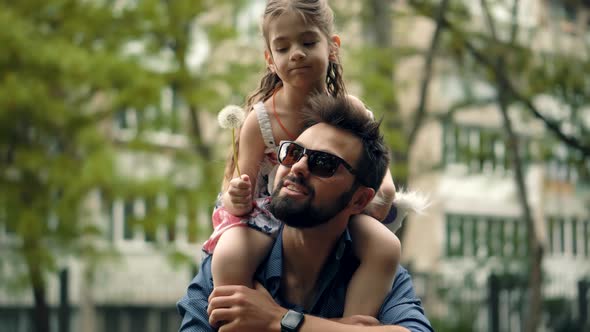 Beautiful Family Father Having Fun On Flower. Little Cute Baby Girl And Father Blowing Dandelion.