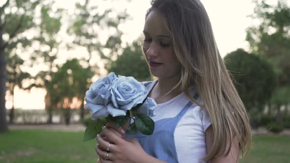 Beautiful Women Smelling blue flowers In a park