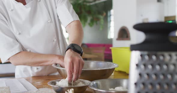 Caucasian female chef adding flour into a bowl