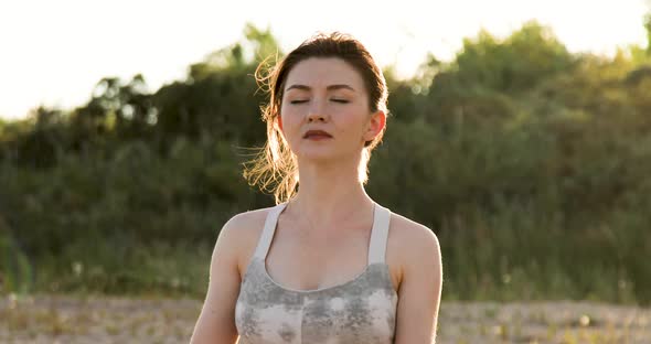 Woman practicing yoga outside in lotus pose on beach during sunset golden hour