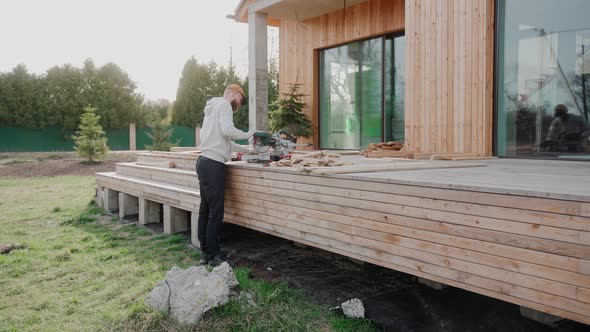 Man Cutting Wood Using Table Saw on Construction Site of a Modern Wooden House