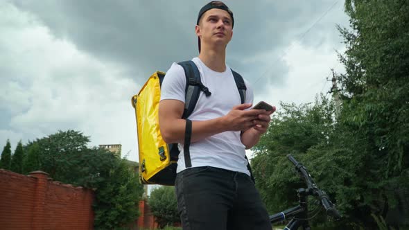 Lost Courier with Smartphone Standing on City Street Surfing Internet Looking Around