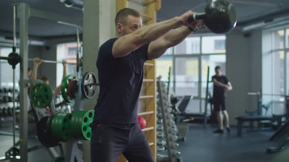 Muscular Man Exercising with Kettlebell in Gym