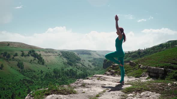 Athletic Girl Practices Yoga on the Edge Mountain