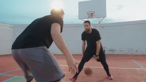 Bearded Male Basketballer dribbling ball and opponent defending the offense