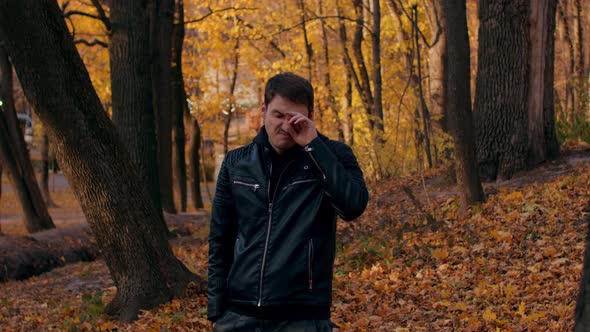Young Man Rubs His Eyes in Autumn Forest