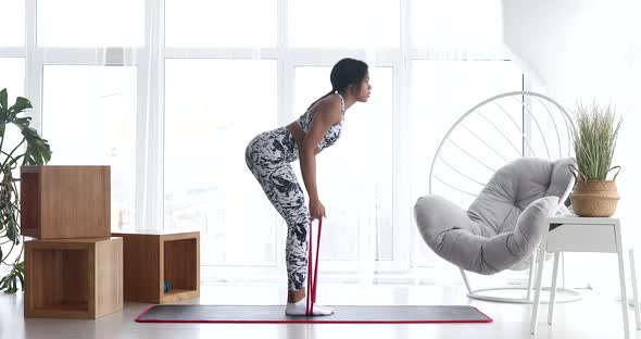 Sporty black woman is training at home in living room.