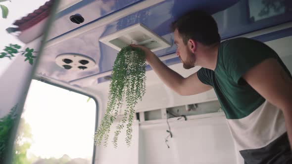 Close up shot of man decorating own van camper with plants and decoration inside interior.