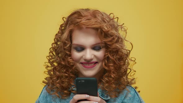 Woman Using Smartphone on Yellow Background. Girl Typing Message on Phone