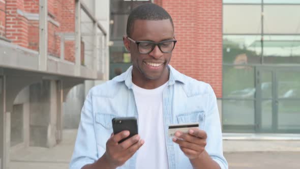 African Man Making Successful Online Payment on Smartphone in Street