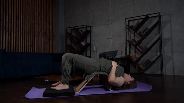 the Woman Has Bent Knees and is Lying on a Sports Mat Against a Gray Wall