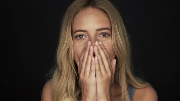 Slow motion shot of woman laughing and then covering face while sneezing