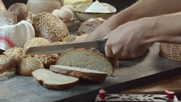 Hands Cutting the Baked Dutch Bread on the Table