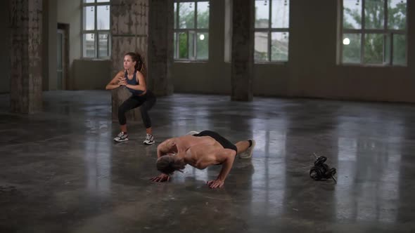 Beautiful Young Sports Couple is Working Out Together in Studio Gymwith Panoramic Window