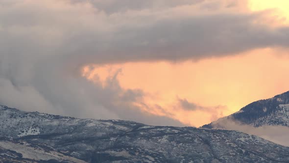 Low foggy clouds moving over snow covered mountains