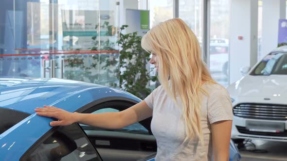 Attractive Woman Smiling To the Camera, Leaning on a New Car at Dealership