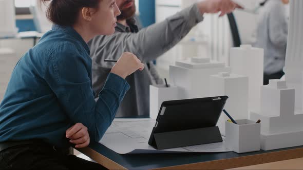 Close Up of Colleagues Working with Tablet and Building Model to Design Construction Layout