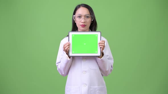 Young Beautiful Asian Woman Doctor Wearing Protective Glasses and Showing Digital Tablet