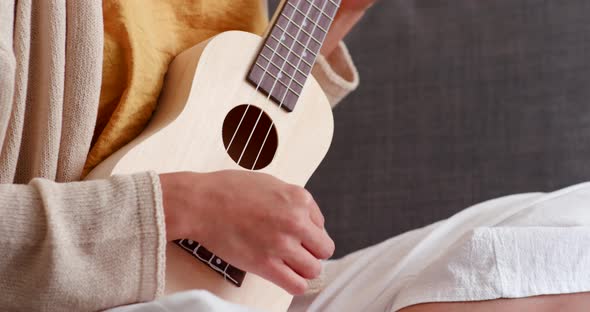 Girl playing ukulele at home