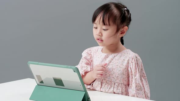 Little Asian girl study online e-learning system using tablet for video call, talking to teacher and