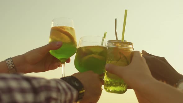 Closeup of hands clinking glasses with green cocktails. Concept of having fun and celebrating holida