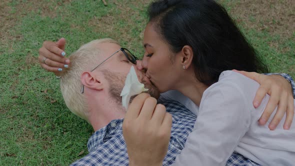 Young International Interracial Couple in Love Lying and Kissing on the Grass on a Sunny Day in a